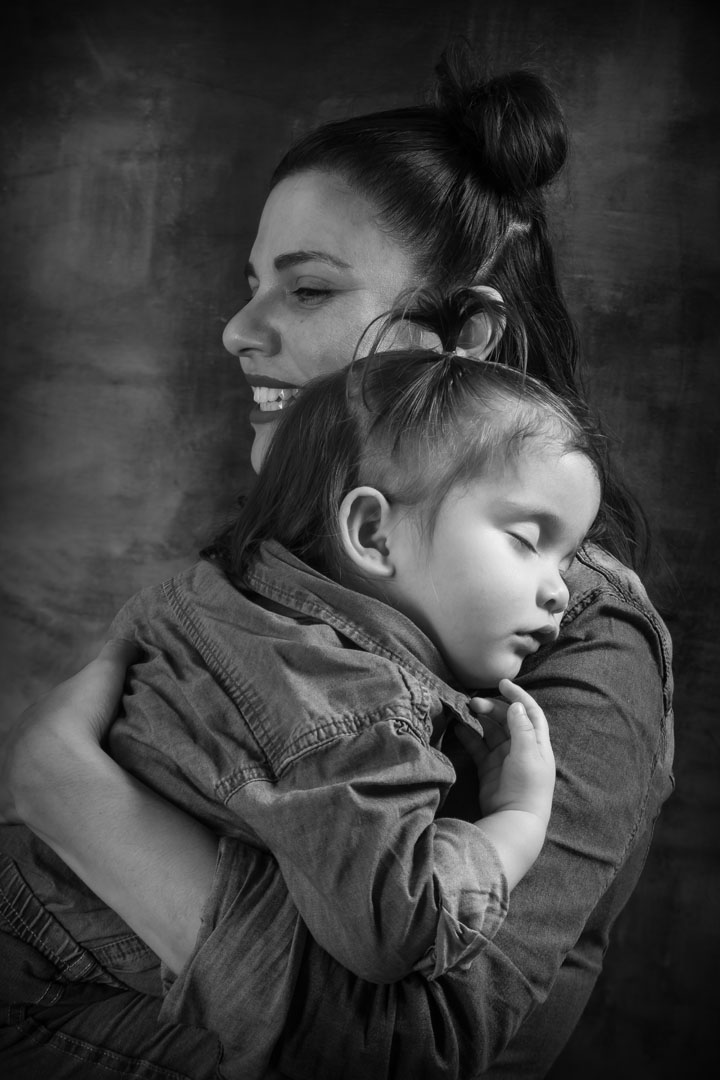 Photo de maman qui découvre une décoration de sapin floqué dans le décor de Noël blanc au Studio Elodie Frigot Photographe